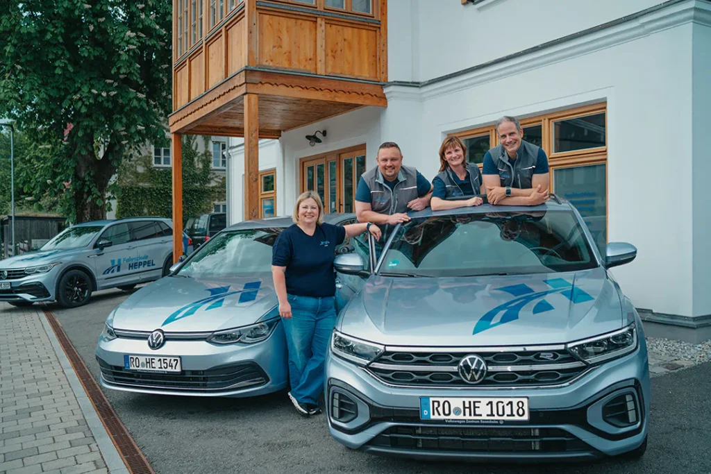 Team der Fahrschule Heppel vor der Fahrschule in Oberaudorf mit drei Fahrschulautos.