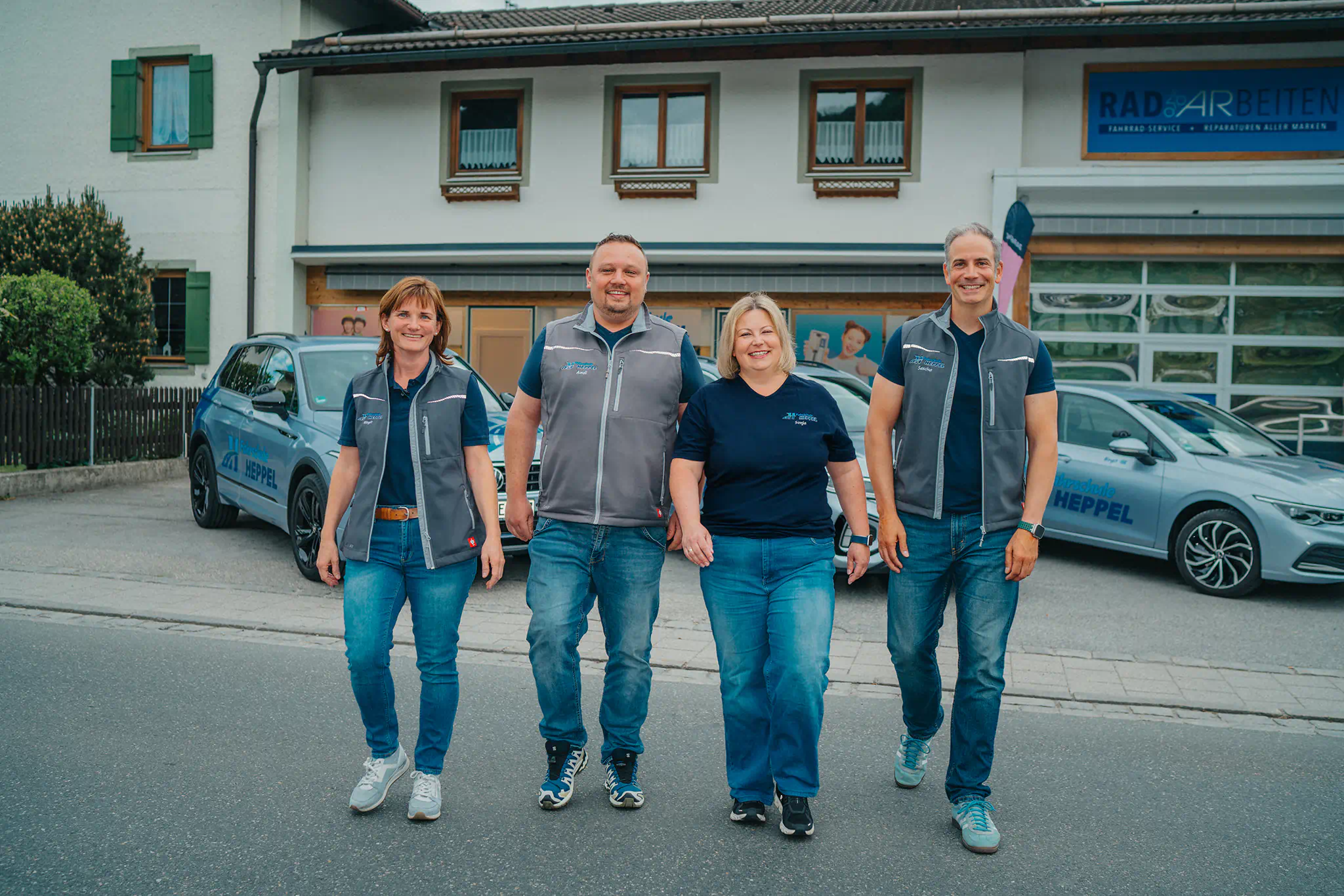 Team der Fahrschule Heppel vor dem Fahrschulgebäude mit Schulfahrzeugen.