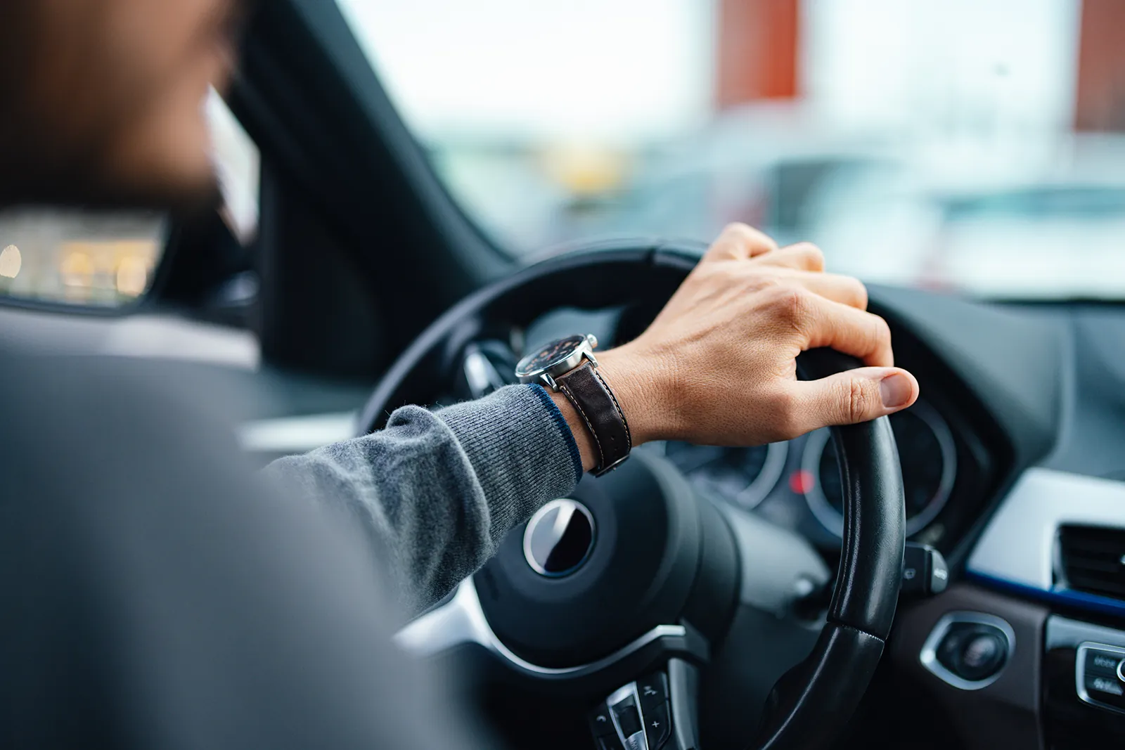 Hand am Lenkrad eines Autos.