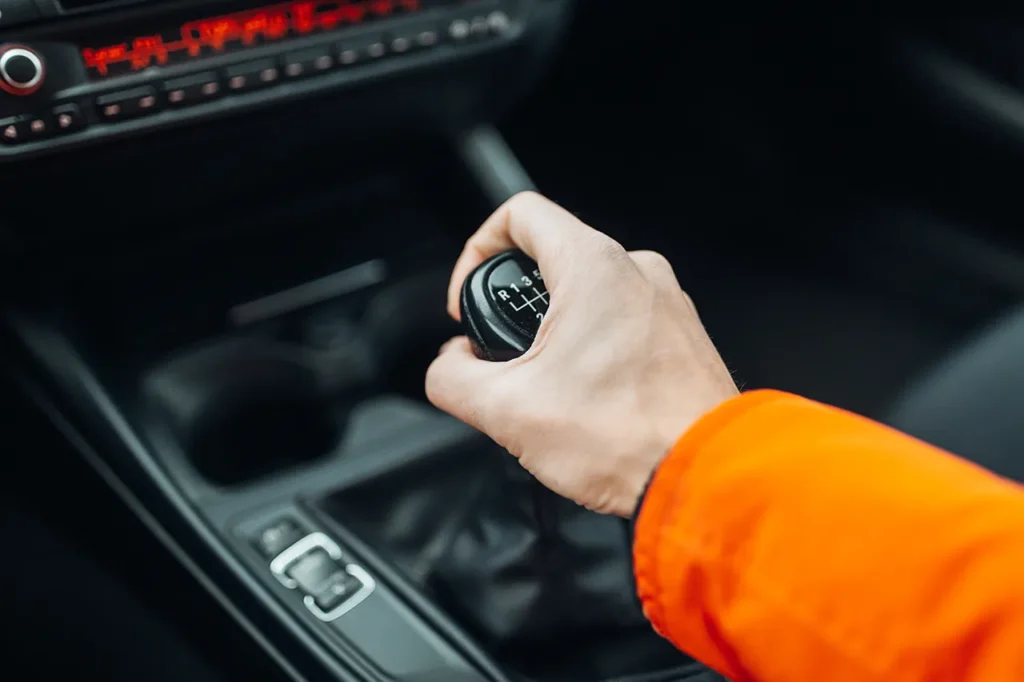 Hand am manuellen Schalthebel im Auto, Blick auf die Mittelkonsole.